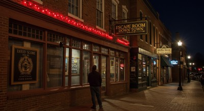 A man standing at sidewalk at night.